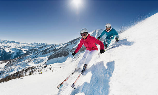 deux personnes qui descendent une piste de ski